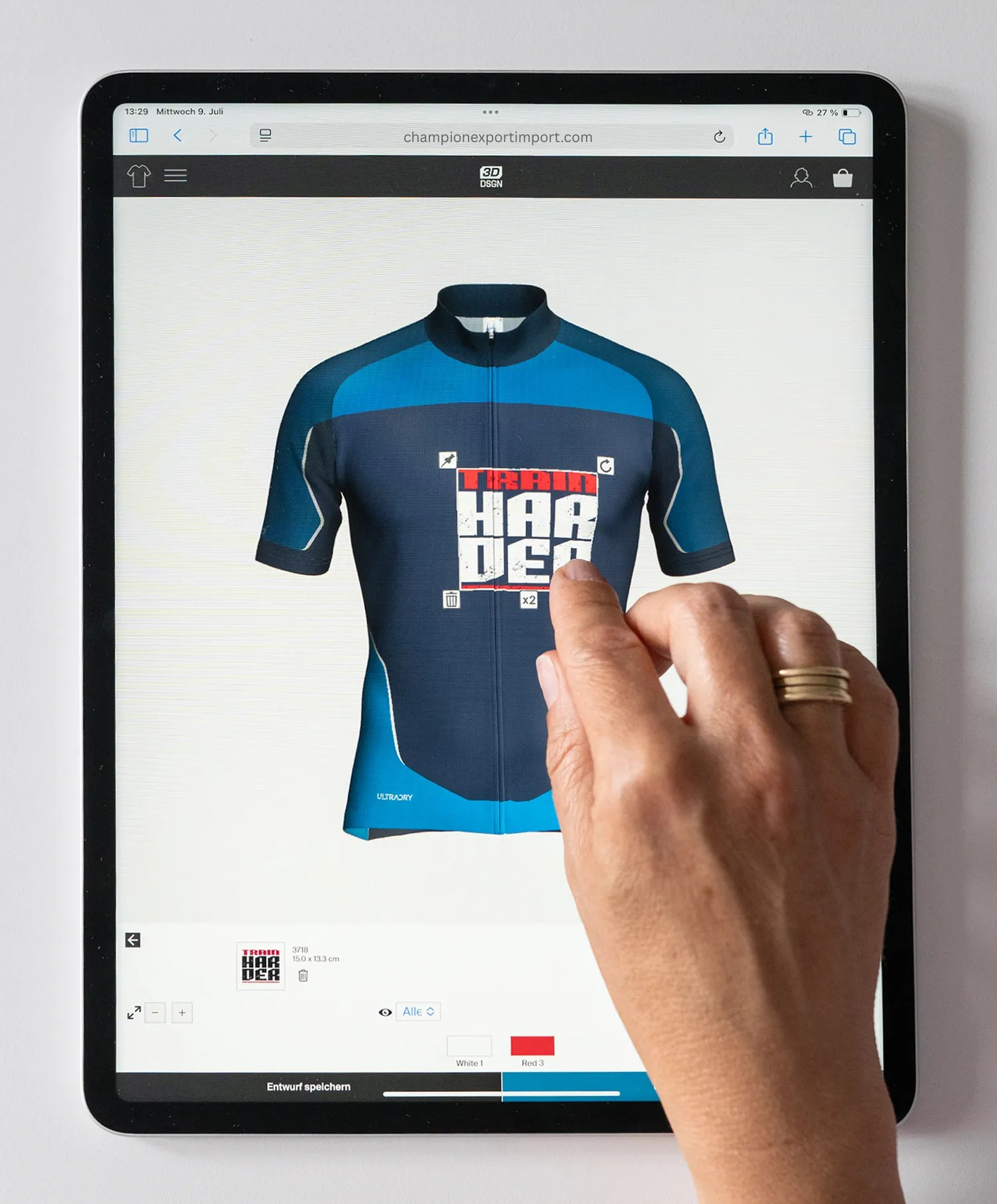 A hand interacts with a tablet displaying the Champion Export Import website, showing a custom-designed blue and dark blue cycling jersey with the text 'TRAIN HARDER'.